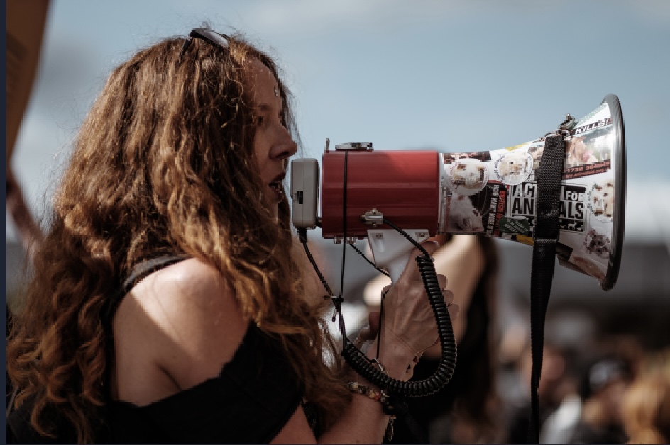 A woman holding a megaphone and shouting into it.